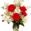Red gerbera daisies and roses in a clear glass vase with white flowers