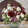 Red and white flower arrangement in a glass vase with a polka-dot ribbon