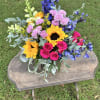 A beautiful arrangement filled with sunflowers, blue delphinium, hot pink spray roses
