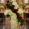 Standing cross covered in white flowers and red roses in a church
