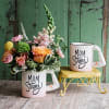 Floral arrangement in a mug with a matching "Mom Strong" mug beside it