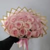 Bouquet of pale pink roses wrapped in gold-edged paper with a pink ribbon