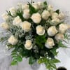 Tall arrangement of white roses and baby’s breath in a clear glass vase