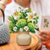 Arrangement of white lilies and green hydrangeas in a ceramic vase