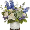 Blue and white floral arrangement in a white vase with a succulent