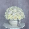 White rose bouquet in a white vase on a pedestal