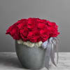 Red roses arranged in a gray pot with a ribbon bow