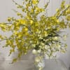 Yellow and white orchid arrangement in a white vase