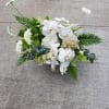 Low arrangement of white orchids and other white flowers with lush greenery in a rectangular silver container
