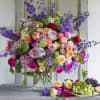 Large mixed bouquet of roses and purple flowers in a glass vase