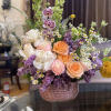 Mixed bouquet of roses, orchids, and small daisies in a textured vase