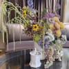 Large mixed floral arrangement in a white vase with cascading blooms