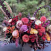 Mixed bouquet of pink, purple, and orange flowers in a white vase