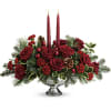 Red rose centerpiece with two lit taper candles in a silver bowl