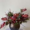 Tropical floral arrangement in a round metallic vase with pink blooms