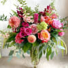 Large mixed bouquet of pink, peach, and orange flowers in a glass vase
