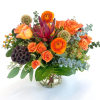 Orange roses and ranunculus in a glass vase with mixed greenery