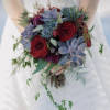 Bride holding a bouquet of red roses and blue-gray succulents