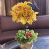 Yellow floral arrangement in a small pot with a blue butterfly accent