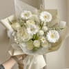 White bouquet with gerbera daisies and roses wrapped in cream paper