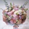 Large pastel bouquet of pink, white, and lavender flowers wrapped in pink paper