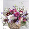 Mixed pink and purple flowers in a woven basket