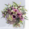 Bouquet of purple calla lilies, roses, and hydrangeas in a clear glass vase