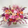 Large bouquet of pink and orange roses with orchids in a gold vase