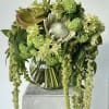 Green floral arrangement in a glass vase with cascading blooms