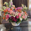Large mixed bouquet in a white vase with pink, orange, and white blooms