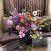 Mixed bouquet in a square glass vase with pink, purple, white, and orange blooms