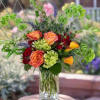 Mixed bouquet of roses and green blooms in a clear glass vase