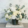 White roses and cream blooms in a glass vase with eucalyptus