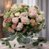 Pink roses and small daisies arranged in a square vase