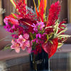 Tropical flower arrangement in a black vase with pink and red blooms