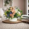 Mixed bouquet of peach roses, white lilies, and blue hydrangeas in a white vase