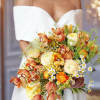 Bride holding a bouquet of orange and cream flowers