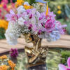 Mixed bouquet with orchids, roses, hydrangeas, and baby's breath in a gold vase