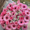 Pink gerbera daisies and roses in a hand-held bouquet