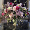 Large mixed floral arrangement in a pedestal vase with pink, white, and purple blooms