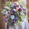 Large bouquet of purple, blue, and pink flowers held by a person