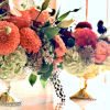 Two colorful floral arrangements in gold pedestal bowls