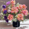 Bouquet of pink, peach, and purple flowers in a black vase