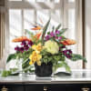 Tropical flower arrangement in a black vase with orange and purple blooms