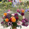 Colorful mixed bouquet in a gold vase with pink, orange, and purple blooms