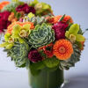 Succulent and orchid bouquet in a green glass vase