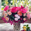 Pink and peach floral arrangement in a glass vase with yellow snapdragons