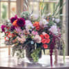 Large mixed bouquet in a glass vase with pink, orange, and white flowers