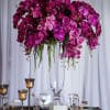 Tall arrangement of purple orchids in a clear glass vase