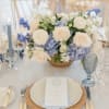 White and pale blue floral centerpiece on a table set for a formal event